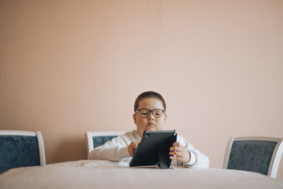 Boy in glasses is intently focused on tablet, suggesting moment of digital exploration