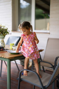 Little girl is eating while sitting on the table on an outside porch