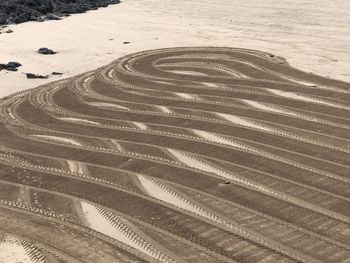 High angle view of tire tracks on sand