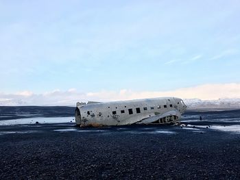 Abandoned airplane on beach against sky