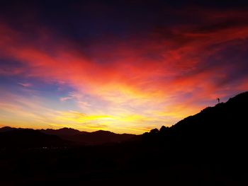 Silhouette landscape against dramatic sky during sunset