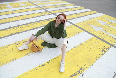 Full length portrait of woman sitting on yellow umbrella