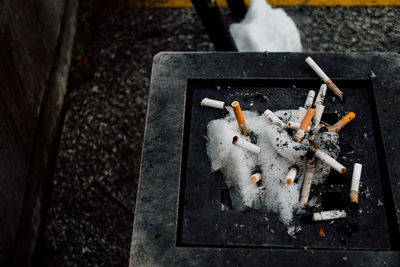 High angle view of cigarette butts on snow covered ashtray