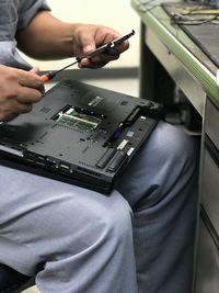 Midsection of man repairing laptop
