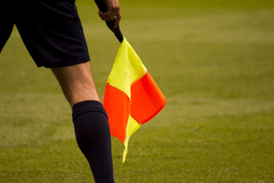 Midsection of man holding flag while standing on field