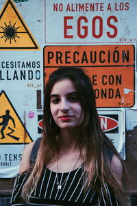 Portrait of smiling young woman standing against posters