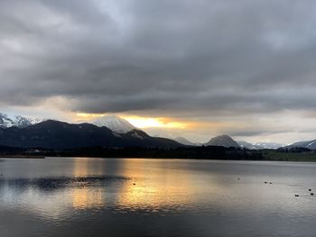 Scenic view of lake by mountains against sky during sunset