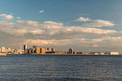 Sea by buildings against sky in city