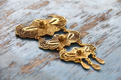 High angle view of golden jewelry on wooden table