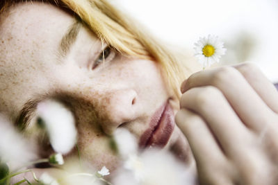 Close-up portrait of beautiful woman against white flowering plants