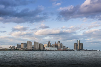 City skyline by river against sky