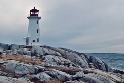 Lighthouse by sea against sky during sunset