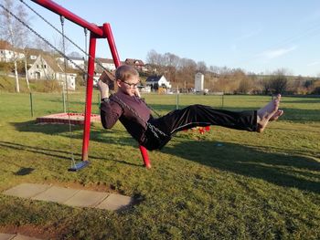 Full length of woman sitting on swing at playground