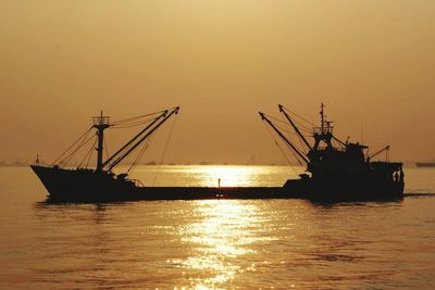 Silhouette ship in sea against sky during sunset