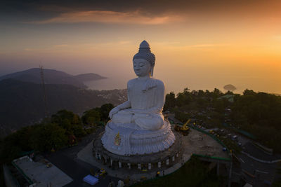 Statue by temple against sky during sunset