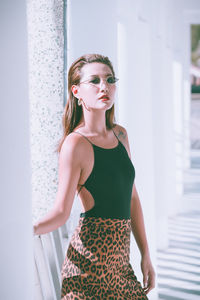 Portrait of beautiful young woman standing against wall