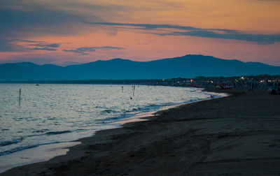 Scenic view of beach against sky at sunset