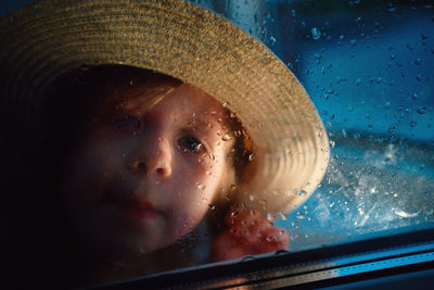 A girl in a straw hat, rain outside the window