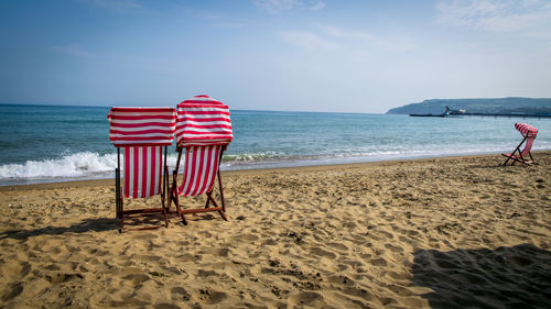 Chairs on beach against sky