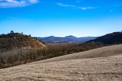 Scenic view of landscape and mountains against blue sky