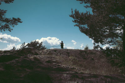 Rear view of man standing on rock against sky