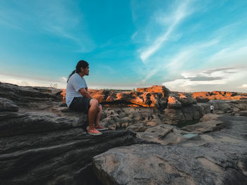 Full length of man standing on rock against sky