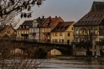 Arch bridge over river amidst buildings against sky