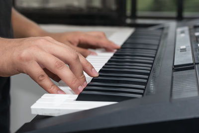 Cropped hands of man playing piano