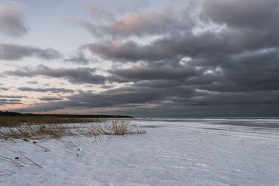 Scenic view of snow covered land and sea against sky