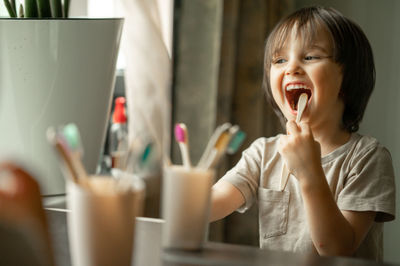 The boy brushes his teeth with a toothbrush made of ecological material