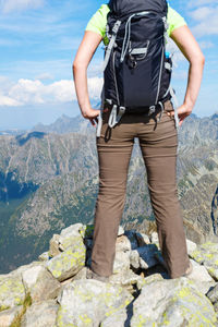 Low section of man standing on rock against sky