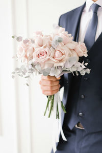 Stylish wedding bouquet of delicate pink roses in the hands of the groom close-up