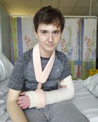 Portrait of boy with fractured hand sitting at hospital