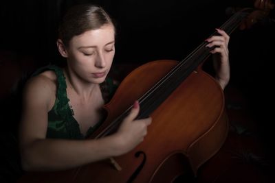 Woman playing violin against black background