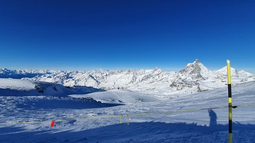 Scenic view of snowcapped mountains against clear blue sky