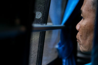 Close-up of man looking through window