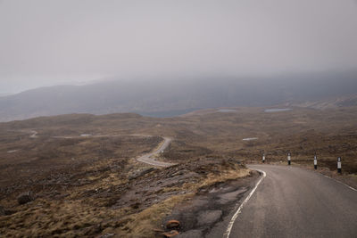 Winding road against cloudy sky