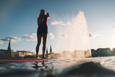 Full length of woman standing by sea in city against sky