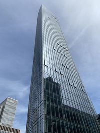 Low angle view of modern glass building against sky