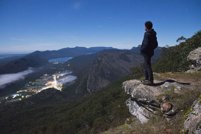 Man standing on rock at mountain against sky