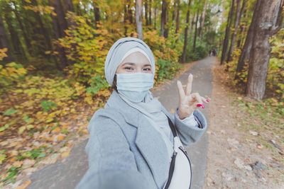 Portrait of woman standing in forest during autumn