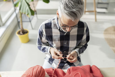 Man knitting woolen sweater at home