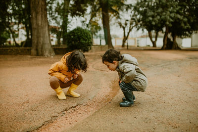 Brother and sister with rubber boots exploring outdoors