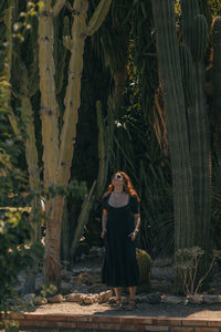 Portrait of woman standing by tree trunk