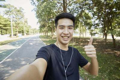 Portrait of young man standing against trees