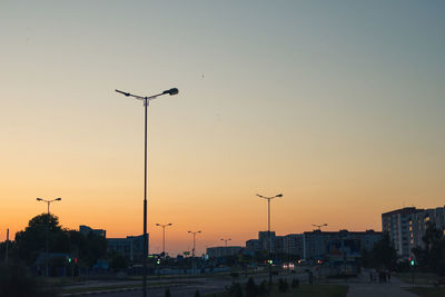 Street lights in city against sky during sunset