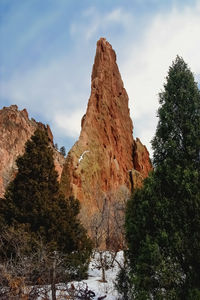 Low angle view of rock formation amidst trees against sky