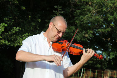 Young woman playing violin while standing on field