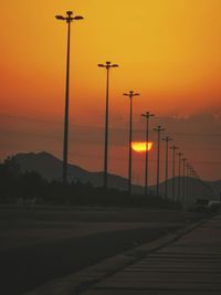 Street lights against orange sky during sunset
