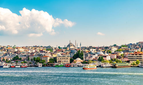 City at waterfront against cloudy sky